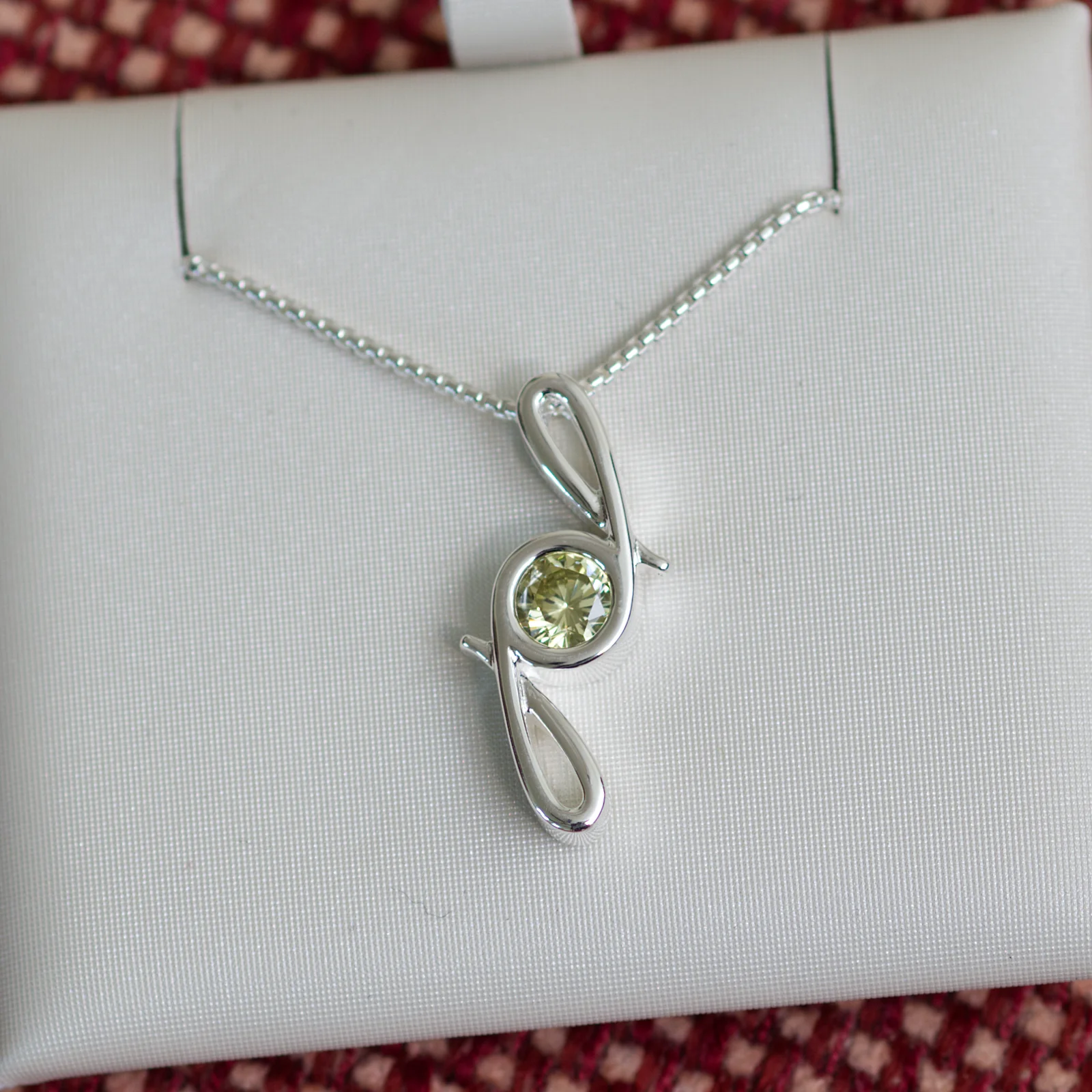 This pendant is made from tarnish resistant silver and features a simulated peridot birth stone. It hangs from a 1mm rounded box chain. The design is a signature motif that symbolizes our message that every life is a precious life.