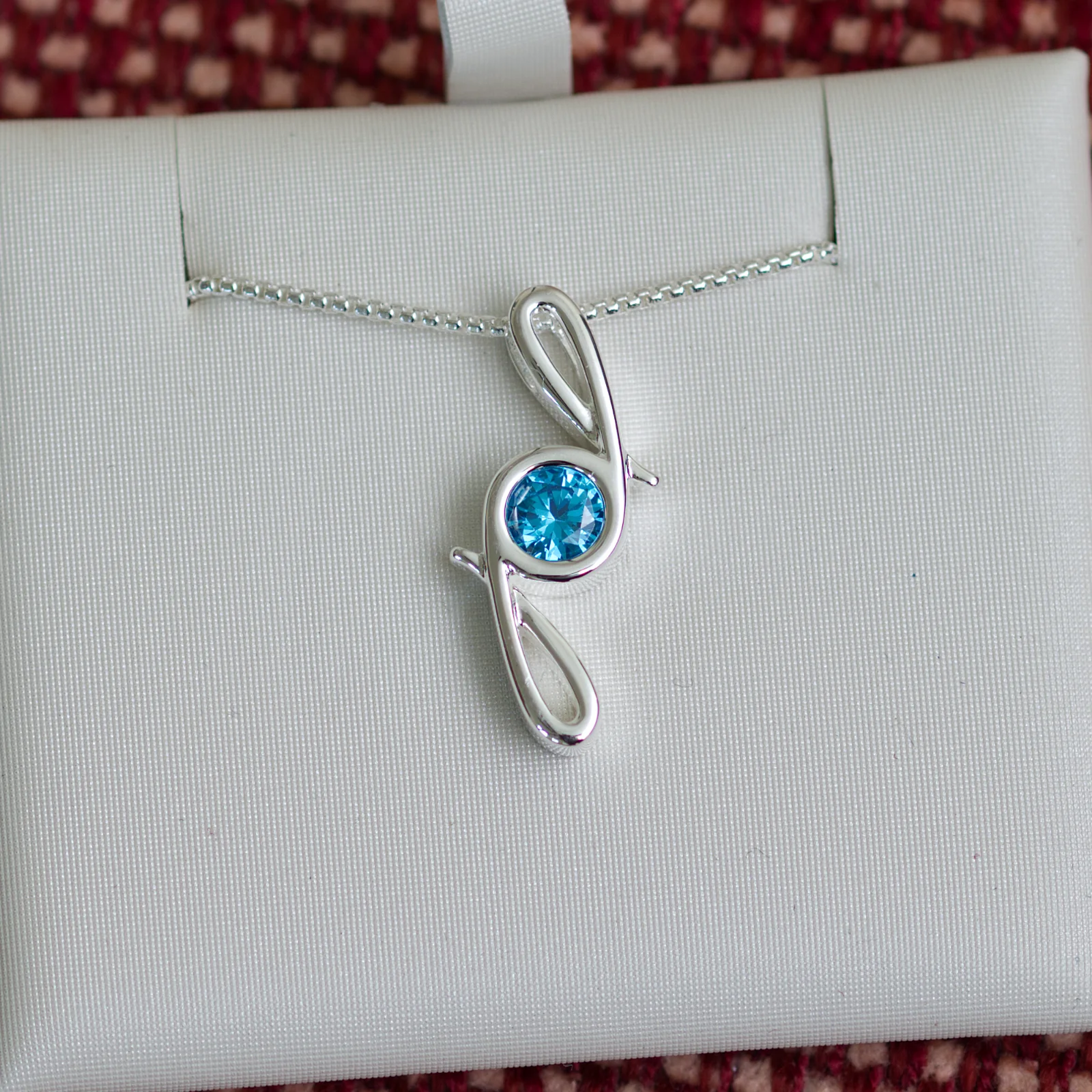 This pendant is made from tarnish resistant silver and features a simulated zircon birth stone. It hangs from a 1mm rounded box chain. The design is a signature motif that symbolizes our message that every life is a precious life.