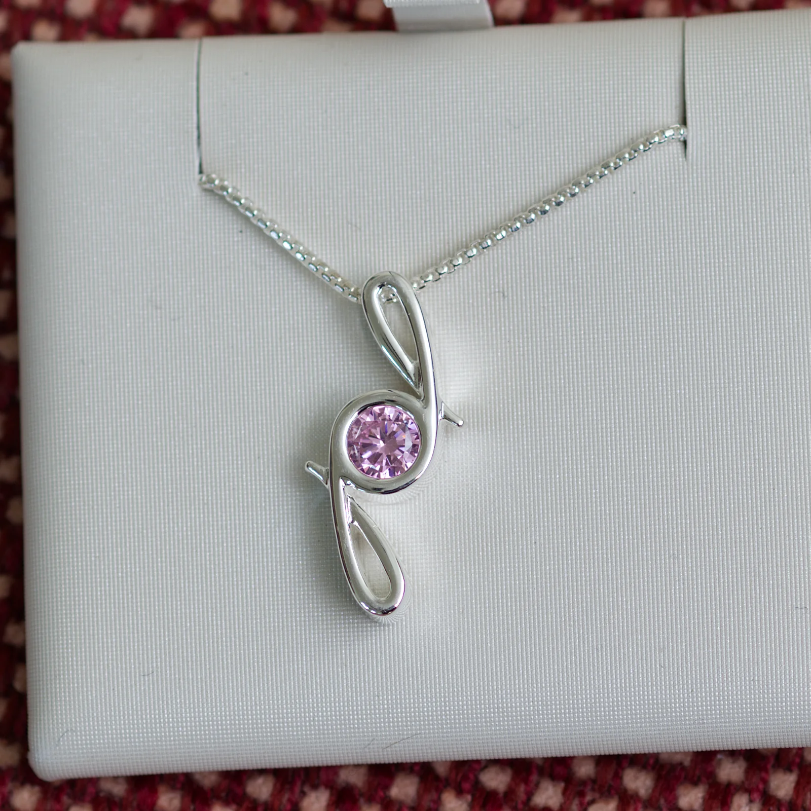 This pendant is made from tarnish resistant silver and features a simulated tourmaline birth stone. It hangs from a 1mm rounded box chain. The design is a signature motif that symbolizes our message that every life is a precious life.